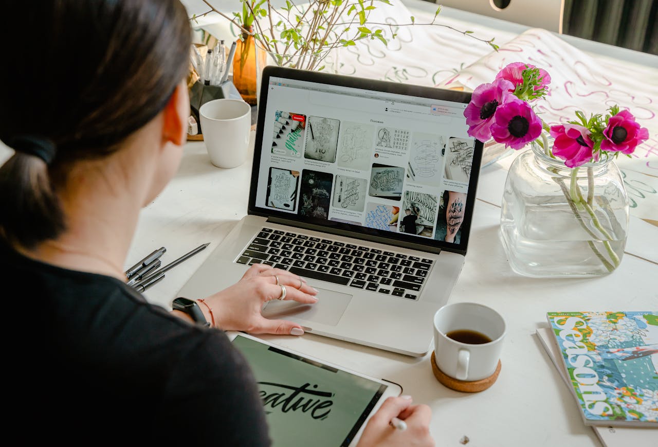 The Art of Drawing Readers In: Your attractive post title goes here Woman in a creative workspace using a laptop and tablet for calligraphy. Artistic and tech-driven environment.